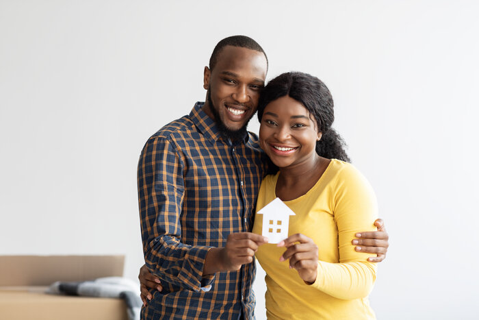 Family Housing Concept. Joyful Black Couple Holding Paper House Figure In Hands - JN Bank