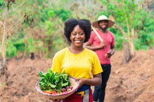 Portrait of a beautiful female African farmer carrying basket of vegetable - JN Bank